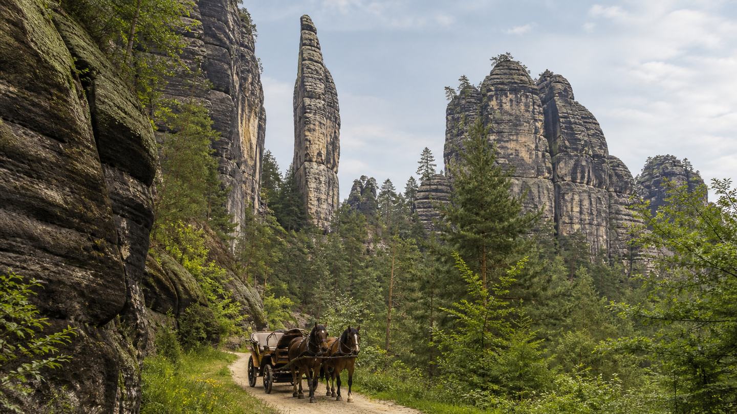 Kleine Kutsche auf einem Talweg unter hohen Sandsteinfelsen der Sächsischen Schweiz. (KI-generiert)
